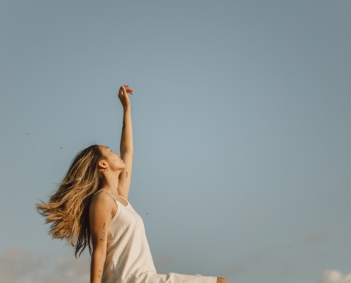 woman in white sleeveless dress raising her right hand