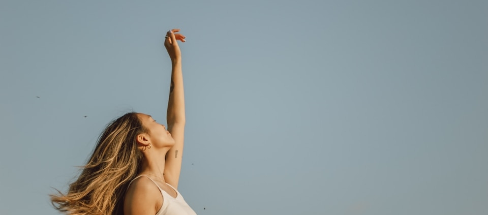 woman in white sleeveless dress raising her right hand