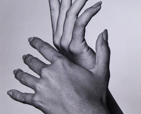 a black and white photo of two hands reaching up