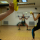 Close-up of a person gripping a barbell with a yellow weight plate during a group workout in a gym