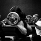 People in a black-and-white gym class performing weighted barbell squats, focus on the central lifter with plate-loaded barbell behind the neck.