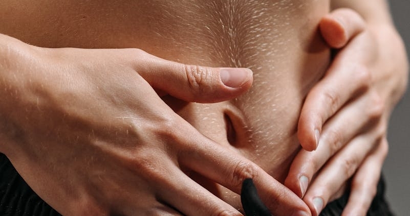 Hands resting on a toned stomach in sportswear, reflecting fitness and health.