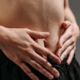 Hands resting on a toned stomach in sportswear, reflecting fitness and health.