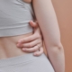 A close-up shot showing a woman's hand on her back in a studio setting, emphasizing texture and form.