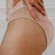 Detailed close-up shot of a woman's hand resting on her waist, showcasing natural skin and stretch marks.