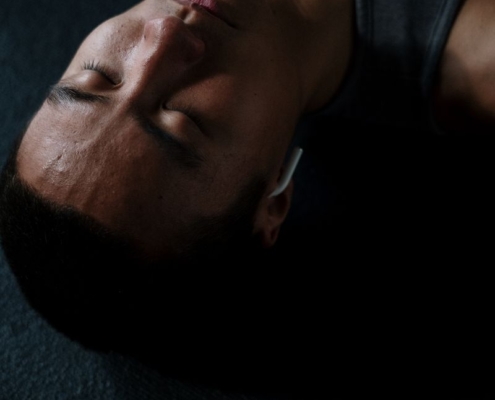 Shirtless man meditating indoors with headphones and eyes closed, embracing relaxation and wellness.