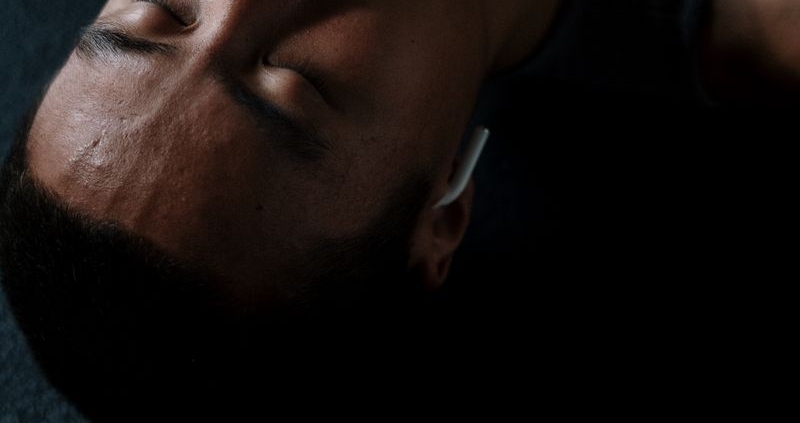 Shirtless man meditating indoors with headphones and eyes closed, embracing relaxation and wellness.