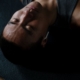 Shirtless man meditating indoors with headphones and eyes closed, embracing relaxation and wellness.