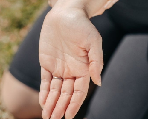 Close-up of a woman's hand holding her wrist outdoors, symbolizing injury or pain relief.