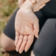 Close-up of a woman's hand holding her wrist outdoors, symbolizing injury or pain relief.