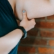 Crop unrecognizable plus size female showing weak arm against brick wall in gym