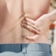 Close-up of a man holding his lower back in pain, possibly indicating discomfort or injury.